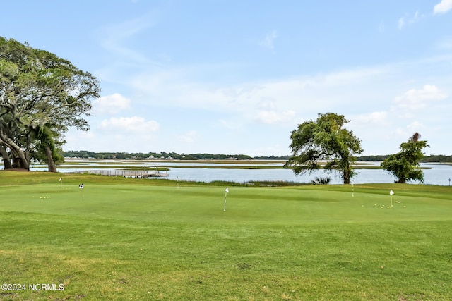 surrounding community with a water view and a lawn