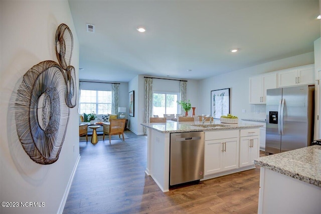 kitchen with white cabinets, a center island with sink, dark wood-type flooring, sink, and stainless steel appliances