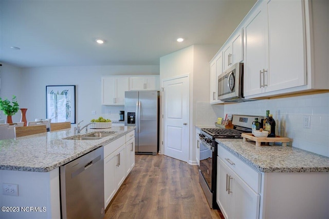 kitchen with stainless steel appliances, sink, hardwood / wood-style floors, and white cabinets