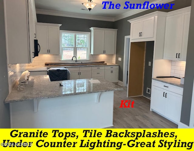 kitchen featuring decorative backsplash, kitchen peninsula, white cabinetry, and a breakfast bar