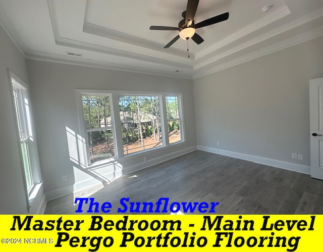 empty room with ornamental molding, dark wood-type flooring, a tray ceiling, and ceiling fan