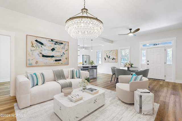 living room featuring ceiling fan with notable chandelier and light wood-type flooring