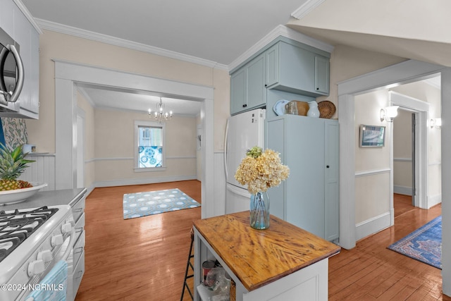 kitchen with white appliances, ornamental molding, a notable chandelier, and light hardwood / wood-style floors