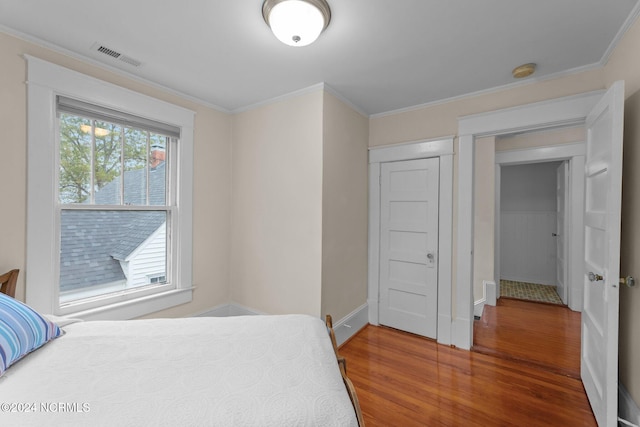 bedroom with hardwood / wood-style flooring, ornamental molding, and multiple windows