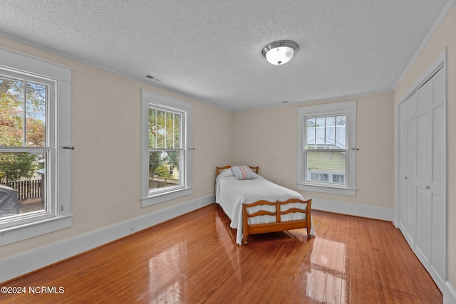 403 Ave D, New Bern, NC 28560 - bedroom featuring a textured ceiling, hardwood / wood-style flooring, multiple windows, baseboards, and crown molding