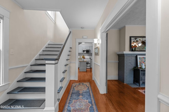 stairway with wood-type flooring and ornamental molding