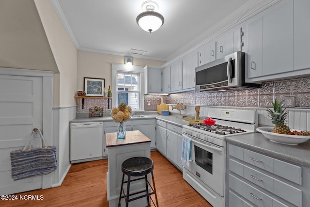 kitchen with a center island, white appliances, ornamental molding, backsplash, and a breakfast bar