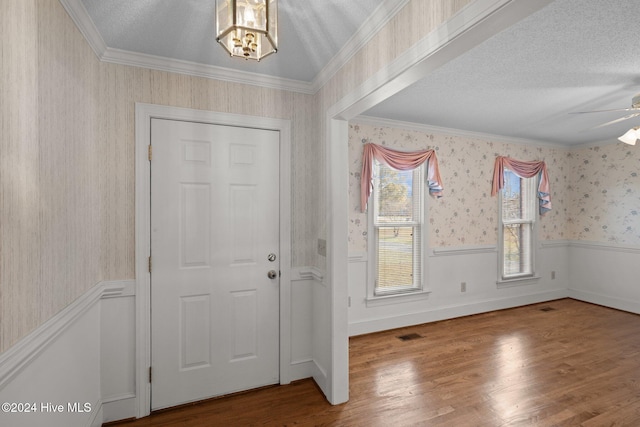 foyer with a textured ceiling, hardwood / wood-style flooring, ceiling fan, and ornamental molding