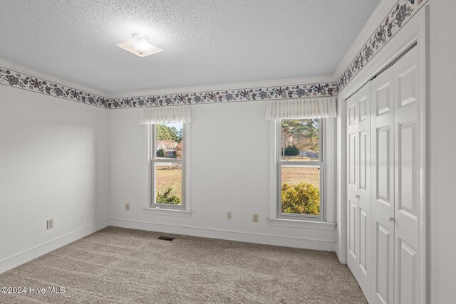 unfurnished living room with light carpet, a textured ceiling, a fireplace, and crown molding