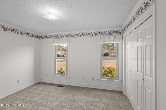 unfurnished room with crown molding, light colored carpet, and a textured ceiling