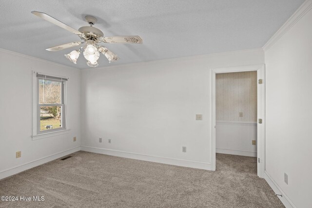 empty room with ceiling fan, crown molding, carpet floors, and a textured ceiling