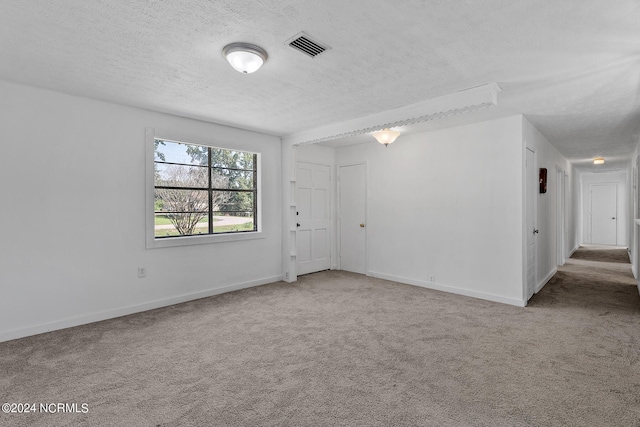 unfurnished room with a textured ceiling and light colored carpet