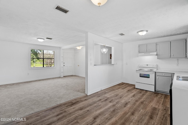 kitchen featuring white range with electric stovetop, a textured ceiling, hardwood / wood-style flooring, and gray cabinetry