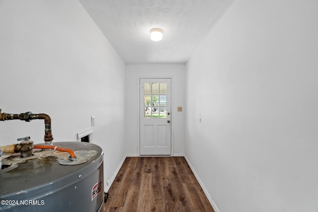 doorway with water heater, a textured ceiling, and dark hardwood / wood-style floors