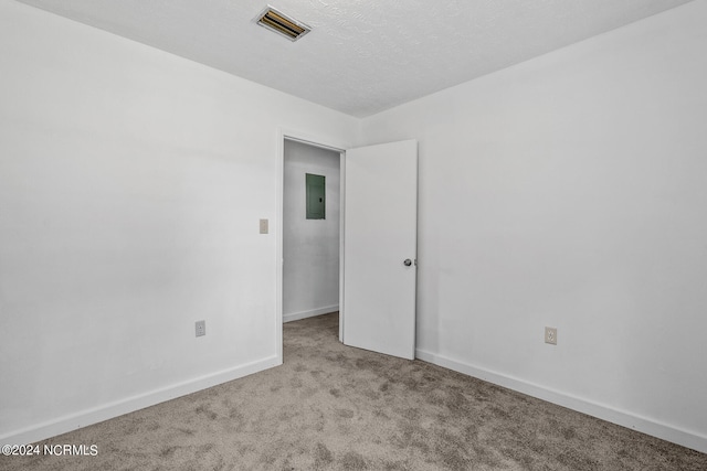 carpeted empty room featuring electric panel and a textured ceiling