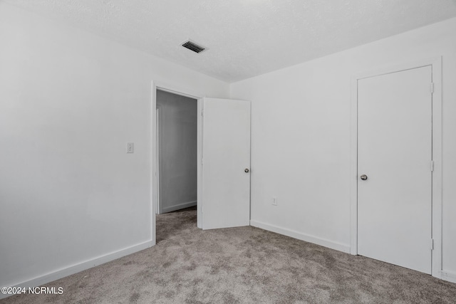 unfurnished bedroom featuring a textured ceiling and light colored carpet