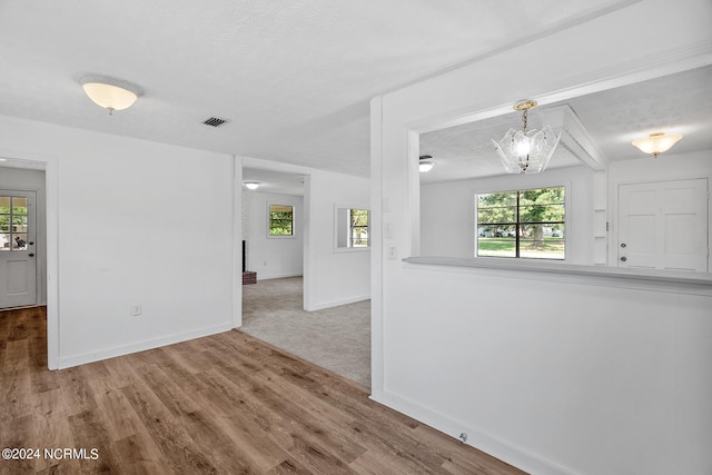 spare room featuring hardwood / wood-style floors, a chandelier, plenty of natural light, and a textured ceiling