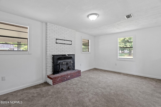 unfurnished living room featuring carpet floors, a textured ceiling, and plenty of natural light