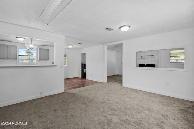 unfurnished living room with a textured ceiling, carpet flooring, and a wealth of natural light