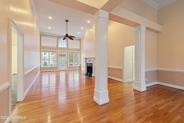 unfurnished living room with ornate columns, ceiling fan, light hardwood / wood-style floors, and a high end fireplace