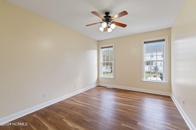 empty room with dark hardwood / wood-style floors, plenty of natural light, and ceiling fan