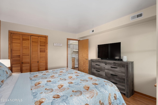 bedroom featuring white fridge, wood-type flooring, and a closet