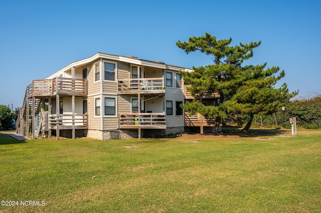 rear view of house with a wooden deck and a lawn