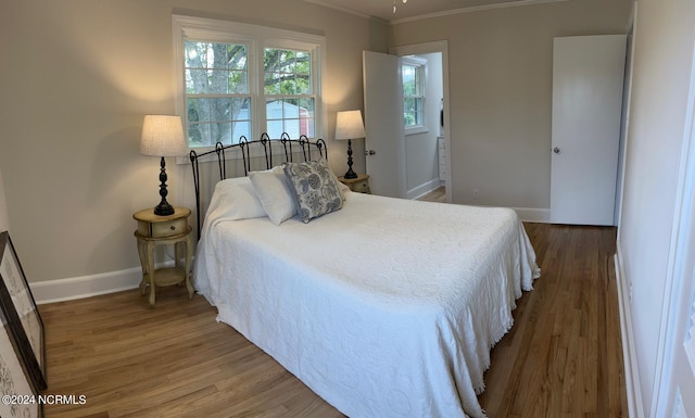 bedroom with ornamental molding and hardwood / wood-style floors