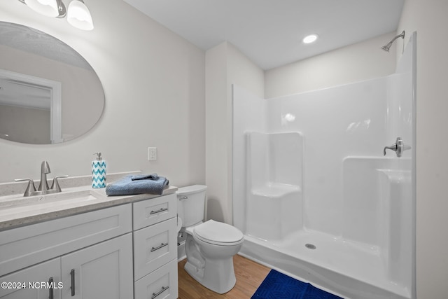 bathroom featuring toilet, vanity, wood-type flooring, and a shower