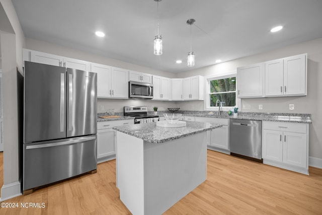 kitchen with appliances with stainless steel finishes, white cabinetry, and light hardwood / wood-style floors