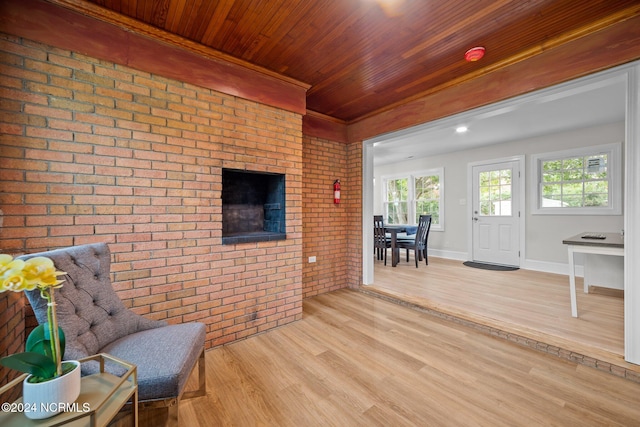 living area featuring light hardwood / wood-style floors, wooden ceiling, and brick wall