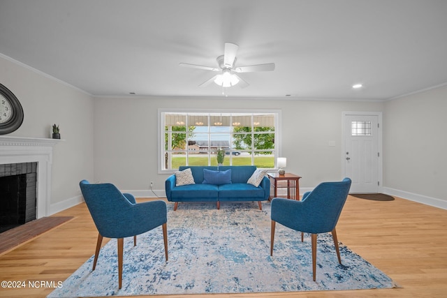 living room with ceiling fan, ornamental molding, light wood-type flooring, and a fireplace