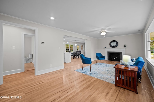 living room with ornamental molding, light hardwood / wood-style floors, and ceiling fan