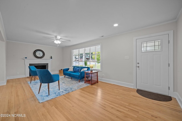 living room with ornamental molding, light hardwood / wood-style flooring, a brick fireplace, and ceiling fan