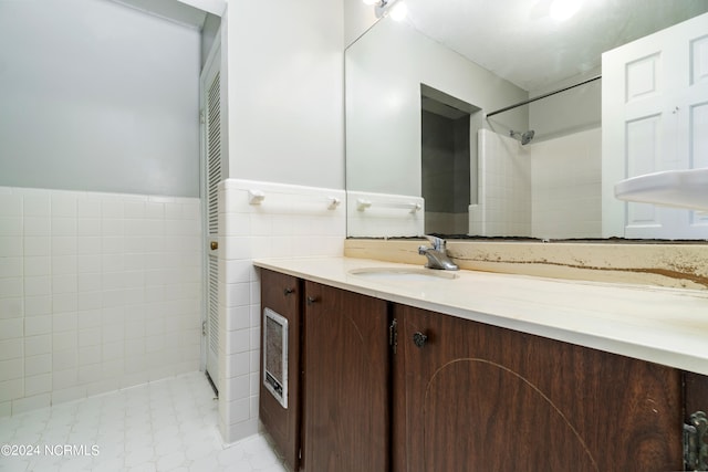 bathroom featuring tile walls, vanity, and a tile shower