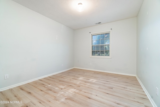 empty room with a textured ceiling and light wood-type flooring