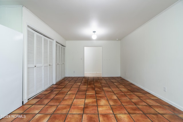 unfurnished bedroom with two closets and dark tile patterned flooring