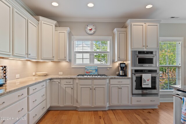 kitchen featuring visible vents, backsplash, appliances with stainless steel finishes, crown molding, and a healthy amount of sunlight