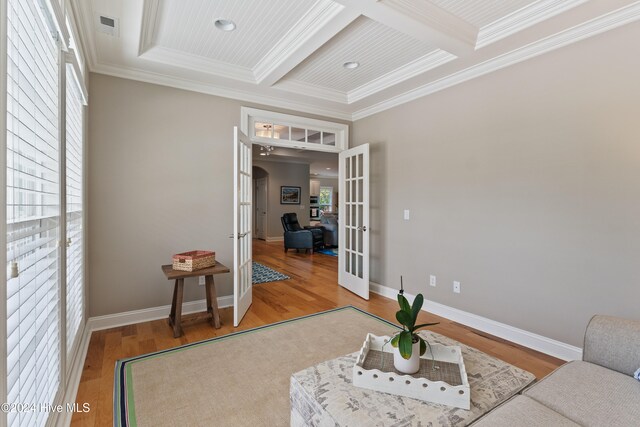 living area with wood finished floors, visible vents, coffered ceiling, ornamental molding, and french doors