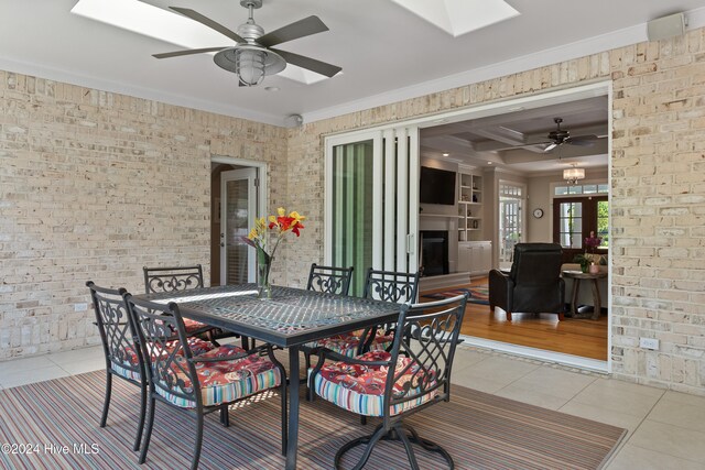 interior space with a skylight, light tile patterned flooring, and brick wall