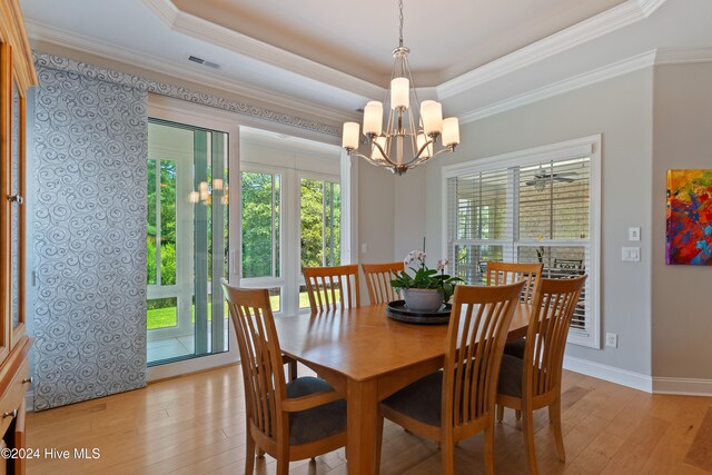 dining space featuring a raised ceiling, crown molding, and light wood finished floors