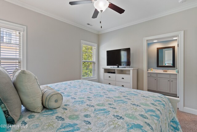 carpeted bedroom with a sink, visible vents, ornamental molding, and ensuite bathroom