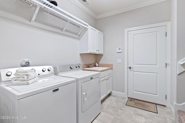 clothes washing area with washing machine and clothes dryer, visible vents, crown molding, cabinet space, and a sink