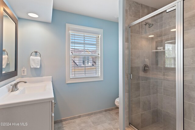 full bath featuring vanity, a shower stall, toilet, and baseboards