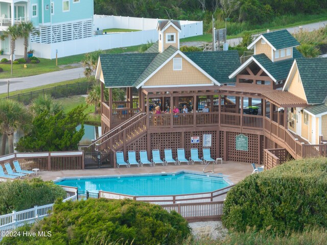 pool featuring a patio area, stairway, a wooden deck, and fence