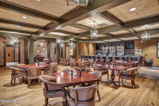 dining area with beamed ceiling, light wood-style flooring, and coffered ceiling