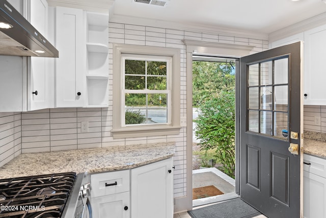 kitchen with wall chimney range hood, white cabinetry, tasteful backsplash, and light stone countertops