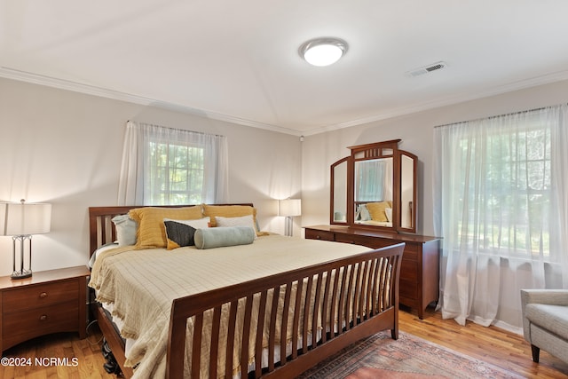 bedroom featuring ornamental molding and light wood-type flooring