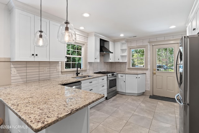 kitchen featuring kitchen peninsula, white cabinets, wall chimney exhaust hood, decorative light fixtures, and stainless steel appliances