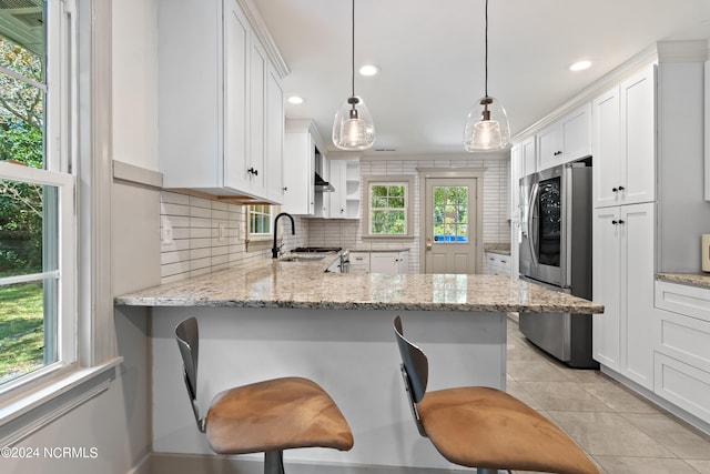 kitchen with kitchen peninsula, a kitchen breakfast bar, white cabinetry, pendant lighting, and stainless steel refrigerator with ice dispenser